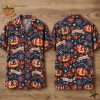 Front and back views of a navy blue short-sleeve button-up shirt hanging on a hanger, covered in an all-over pattern of flag-decorated jack-o'-lanterns wearing tricorn hats, orange maple leaves, fireworks bursts, and ribbon banners reading AMERICA 250 and 1776-2026.