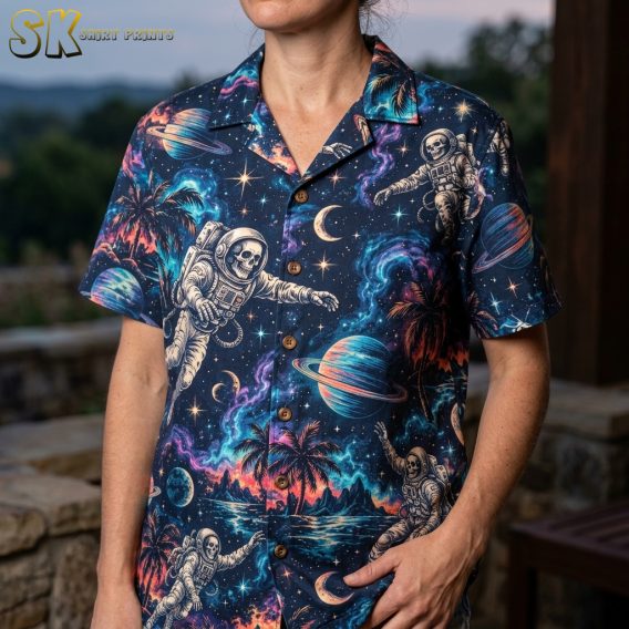 Close-up of a woman wearing a dark navy Hawaiian shirt, showing detailed artwork of cream astronauts, colorful nebulae, ringed planets, and palm tree silhouettes.