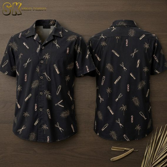 Front and back of a black short-sleeve button-up shirt displayed flat, showing an all-over pattern of scissors, combs, clippers, straight razors, barber poles, and palm trees printed in beige and muted tones.
