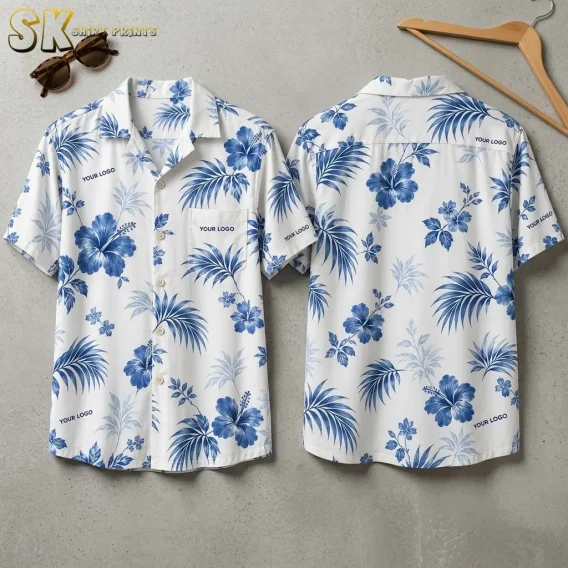 Both the front and back of a white custom Hawaiian shirt with company logo placeholders are laid flat, showing large blue hibiscus flowers, palm fronds, and multiple 'YOUR LOGO' text positions across the chest, sleeves, and back.