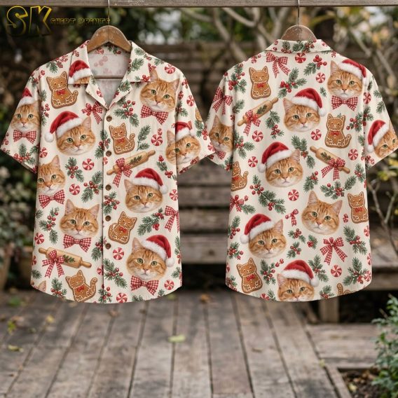 Two sides of a mens Christmas Hawaiian shirt hang on wooden hangers outdoors, displaying the full repeat pattern of Santa hat–wearing tabby cat faces, gingerbread cookies, peppermint rounds, and festive bows on a beige ground.
