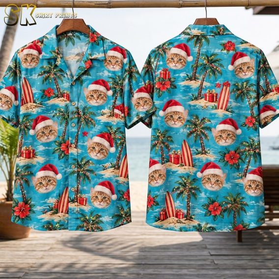 Front and back of the hawaiian shirt with Santa-hat cat faces hang on wooden hangers against a bright beach backdrop, showing the full repeat of the turquoise all-over pattern on both sides.