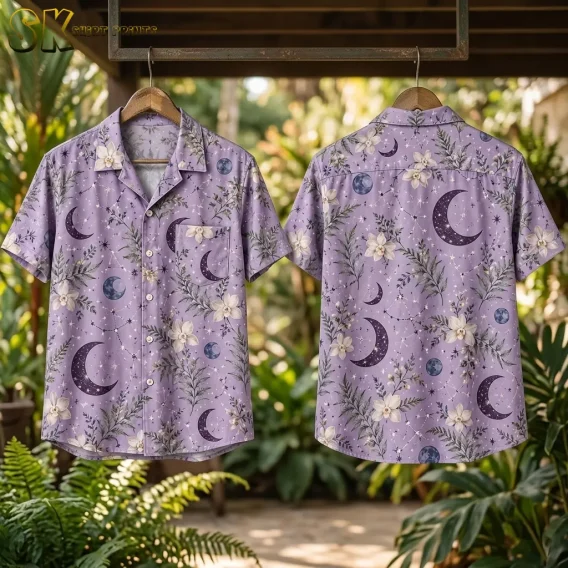 The lavender celestial shirt shown front and back on wooden hangers suspended outdoors, with tropical foliage behind, highlighting the large crescent moon on the back and the chest pocket on the front.