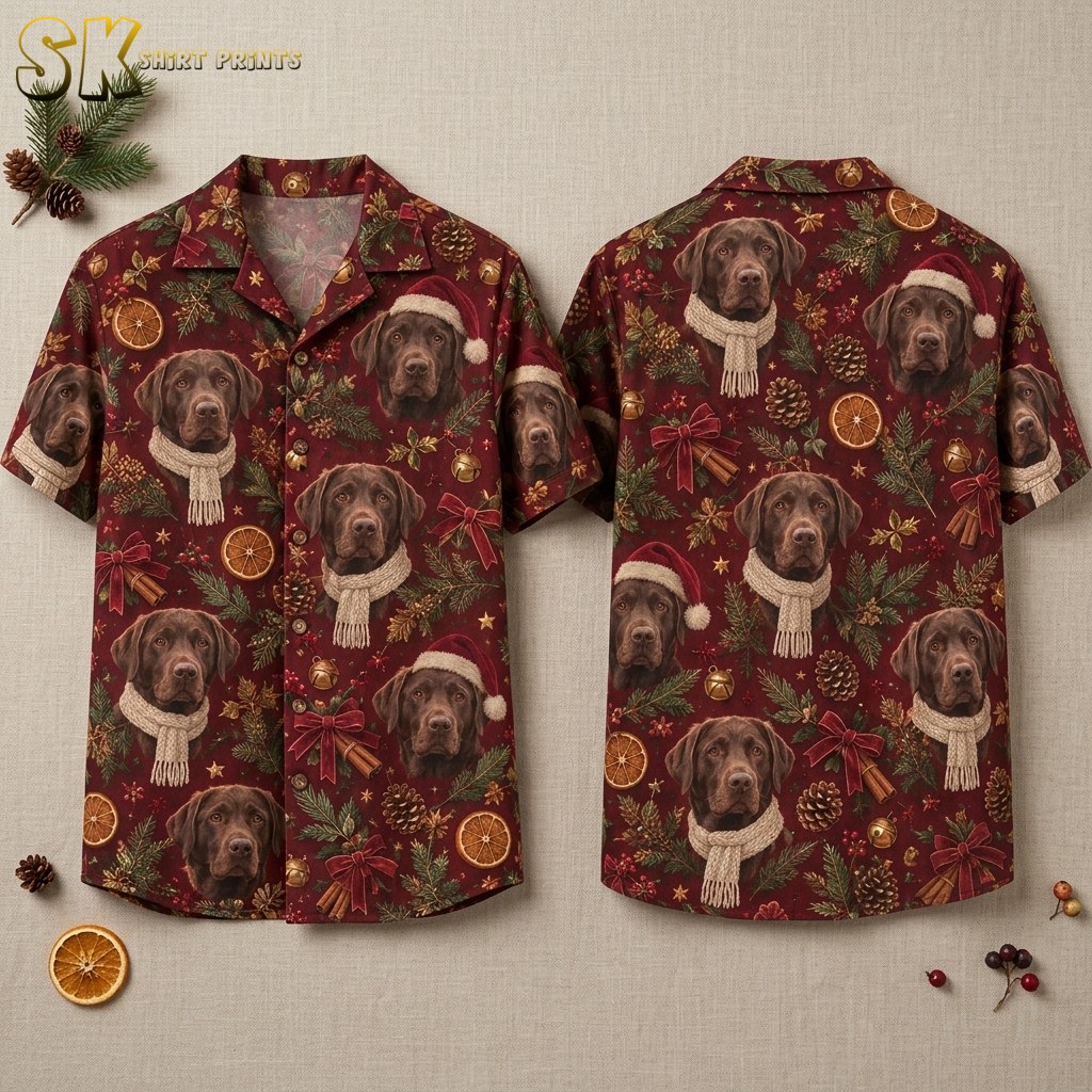 Front and back of a burgundy hawaiian style christmas shirt laid flat on a neutral surface, showing realistic chocolate Labrador faces wearing Santa hats and knitted scarves surrounded by pinecones, dried orange slices, and red bows.