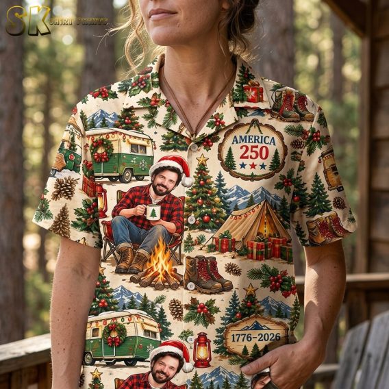 Close-up view of the shirt on a woman, highlighting the detailed illustrative artwork including the campfire scene, green camper van motifs, and holly berry clusters on the beige fabric.