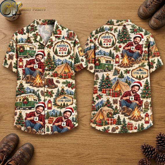 Front and back hanger views of a short-sleeve button-up shirt with a beige background printed with campfire scenes, vintage green camper vans, pine trees, and a man in a Santa hat; text plaques read AMERICA 250 and 1776-2026.