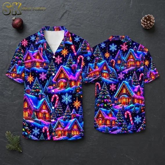 Front and back of a navy short-sleeve shirt with colorful snowy cottages and Christmas trees, arranged on a dark gray surface.