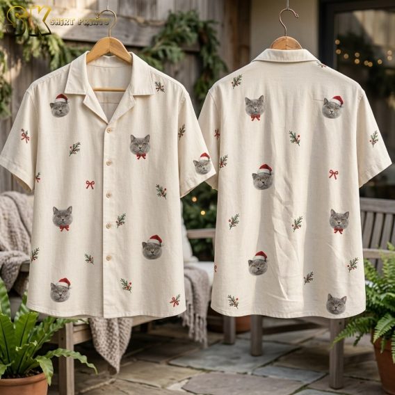 Front and back of the christmas santa hawaiian shirt hang side by side on a wooden hanger outdoors, displaying gray cat faces with Santa hats, red bow ties, holly clusters, and small red bows evenly distributed across the cream fabric.