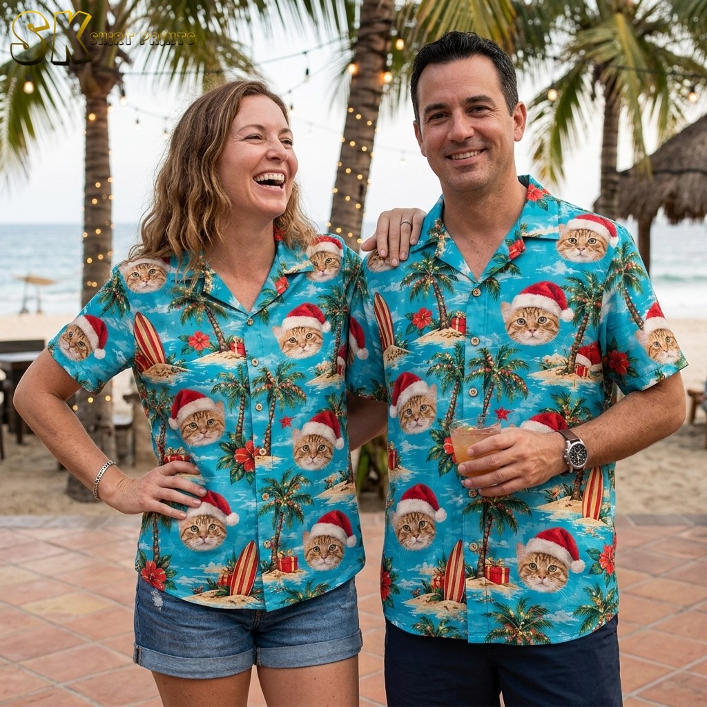 A laughing woman and a smiling man both wearing the same tropical Christmas shirt stand together near a beach, the turquoise pattern of Santa-hat cat faces clearly visible on both.