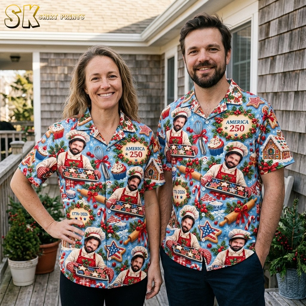 A woman and a man stand together on a covered porch, both wearing the same light blue Christmas baking print shirt featuring the chef figure and 'AMERICA 250' wreath text.