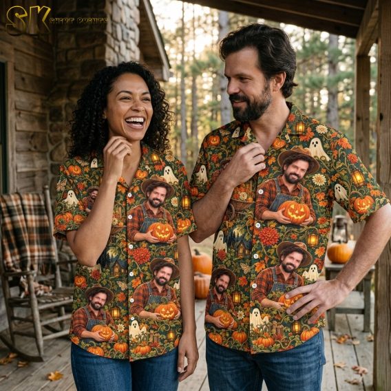 A laughing woman and a smiling man stand together on a rustic cabin porch, both wearing the same halloween aloha shirt printed with pumpkins, ghosts, and glowing lanterns on a dark green ground.