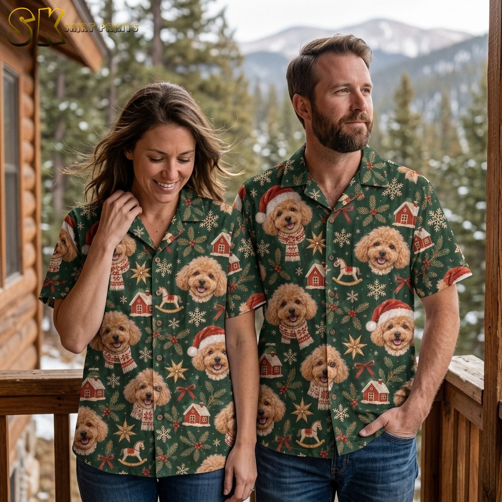 A man and woman wearing matching christmas aloha shirts stand together on a wooden deck overlooking a snow-dusted pine forest and mountains.