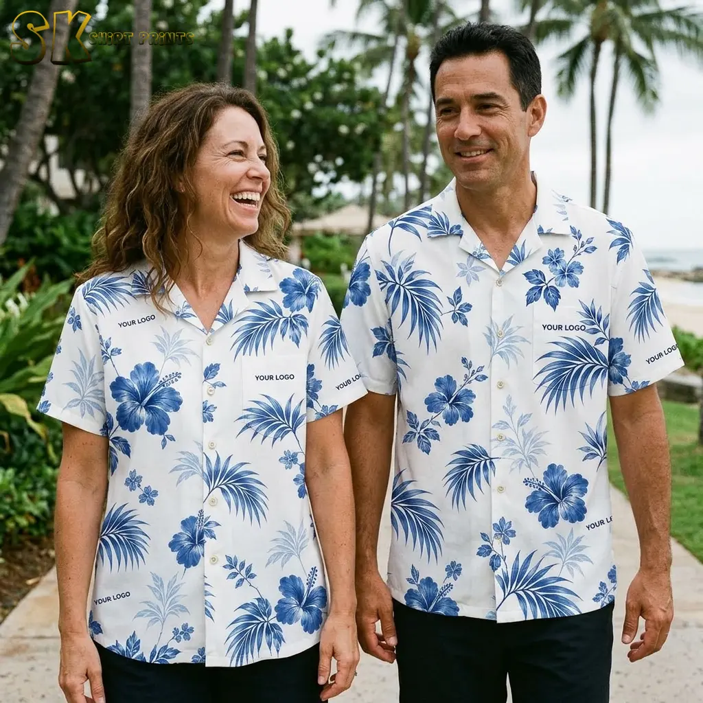A laughing woman and a smiling man walk side by side wearing matching white logo Hawaiian shirts, with palm trees and a beach visible in the background.
