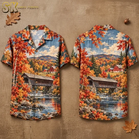 Front and back of a short-sleeve shirt displayed on a tan background, featuring a covered bridge, river, and colorful fall trees.