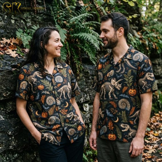 A couple shown together in a lifestyle setting, with one person wearing the black dinosaur skeleton and pumpkin camp collar shirt.