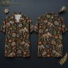 Front and back hanger views of a black short-sleeve button-up camp collar shirt printed with skeletal dinosaurs, carved jack-o'-lanterns, crescent moons, ammonite fossils, and fern leaves in beige, orange, and green on a black ground.