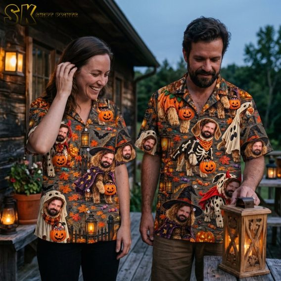 A couple wearing matching or coordinating Halloween-themed Hawaiian shirts printed with costumed bearded dogs carrying jack-o'-lantern candy buckets on a dark background of bats, carved pumpkins, and autumn leaves.