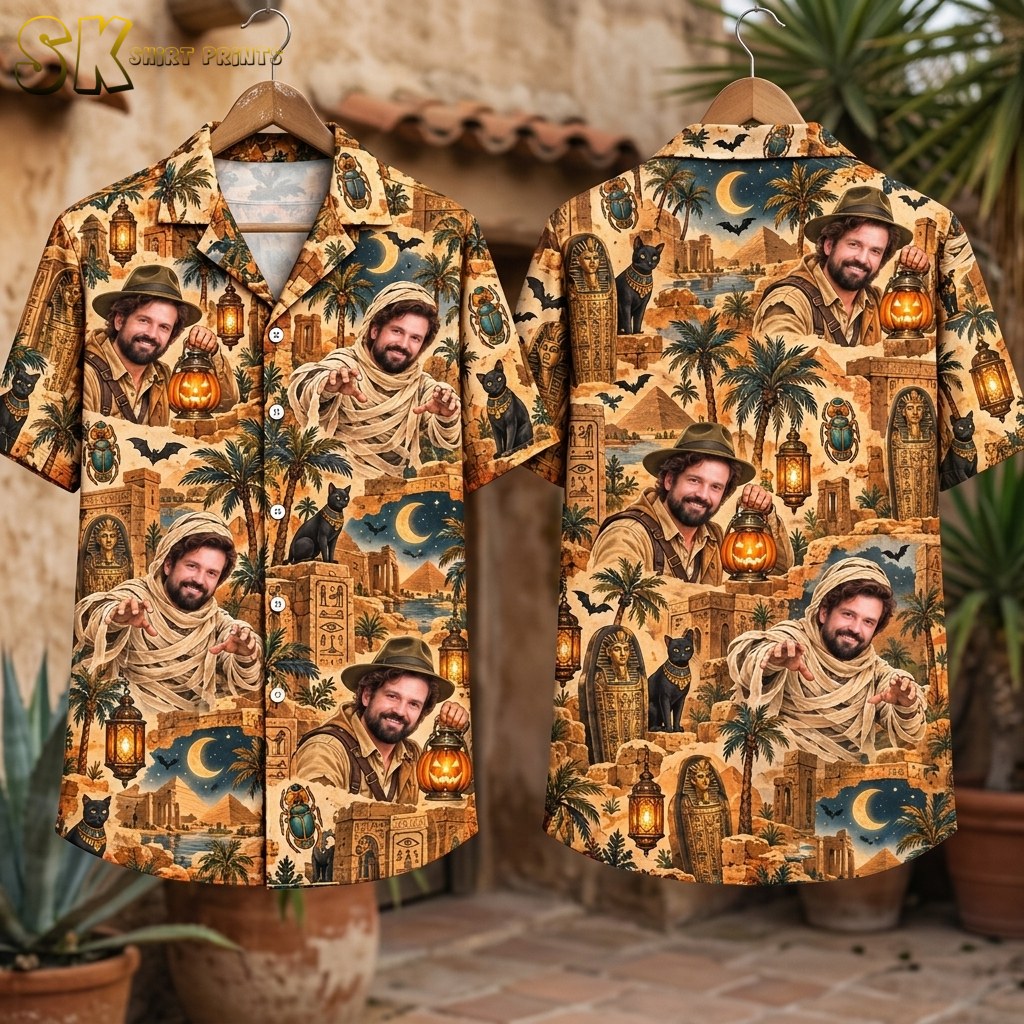 Flat-lay front and back views of the short-sleeve button-up shirt spread out to show the full sandy beige pattern, including pyramids, sarcophagi, black cats, bats, palm trees, and glowing lanterns arranged in a dense all-over collage layout.