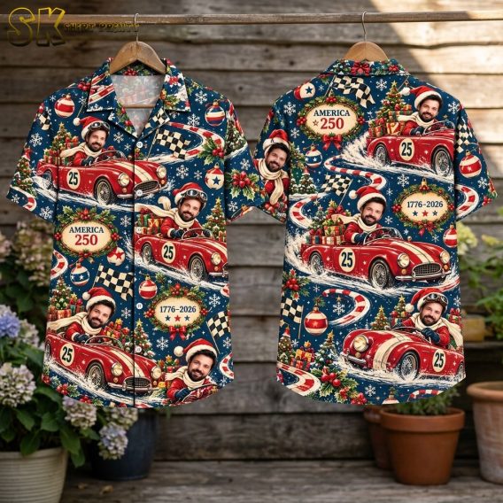 The shirt is displayed front and back on a flat surface outdoors among potted plants and wooden boards, showing the full repeat pattern including the checkered race flags and Christmas ornament motifs on both sides.
