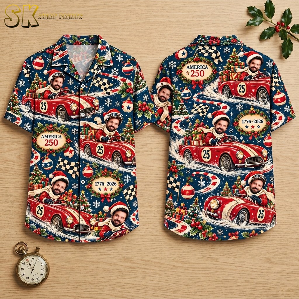 Both sides of a dark blue short-sleeve button-up shirt shown flat on a hanger, featuring a repeating pattern of a Santa-hatted vintage race car driver, checkered flags, Christmas trees, and oval plaques reading 'America 250' and '1776–2026'.
