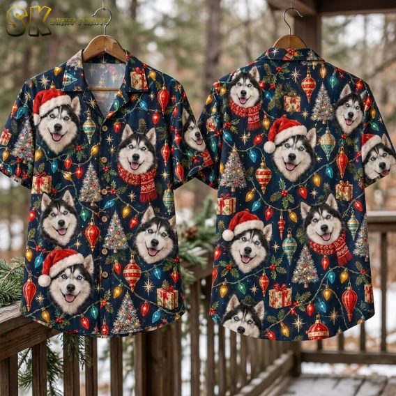 Front and back of the navy husky Christmas shirt hang side by side on wooden hangers against a snowy outdoor backdrop, with pine branches in the foreground framing the all-over holiday pattern.