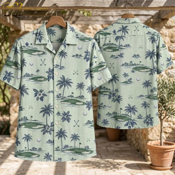 Two company logo Hawaiian shirts hang on wooden hangers against a rustic stone wall, one showing the front with palm trees and golf course scenes and one showing the back with crossed clubs and a putting green flag.