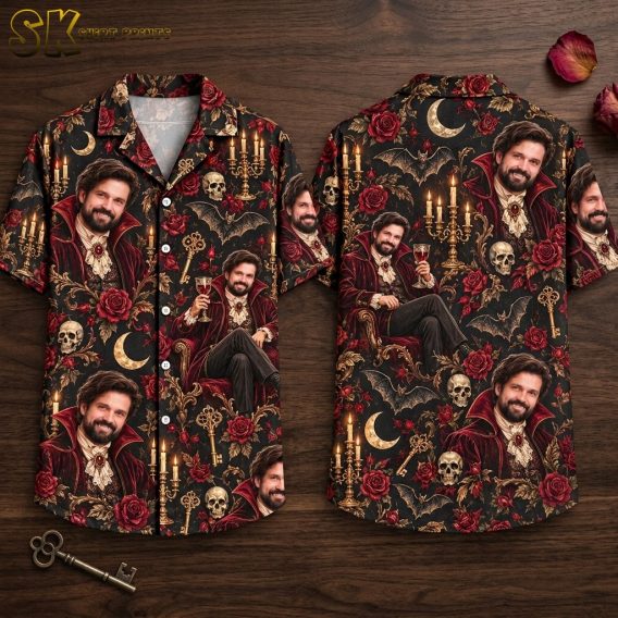 Front and back hanger view of a black short-sleeve button-up shirt printed with a repeating Victorian vampire figure seated in a velvet armchair holding red wine, surrounded by gold candelabras, red roses, crescent moons, skulls, and black bats.