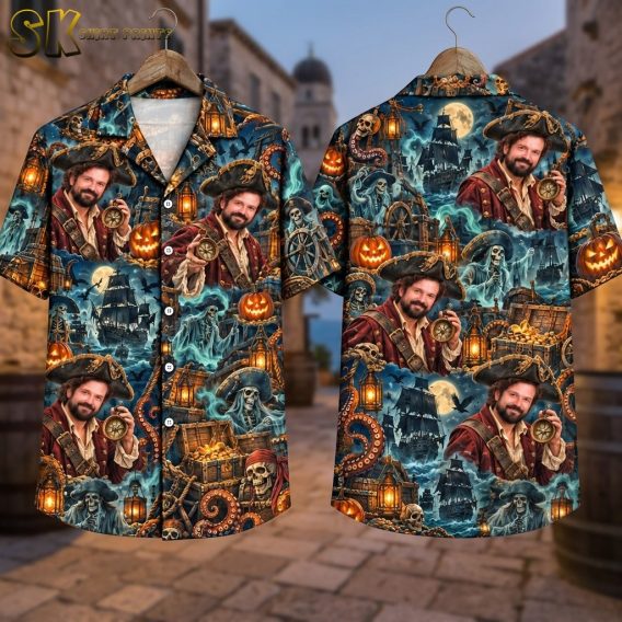 Front and back of the halloween aloha shirt are displayed on wooden hangers against a stone alley backdrop, showing the full moon and tall ship scene on the back panel alongside the compass-holding pirate portrait repeated across both sides.