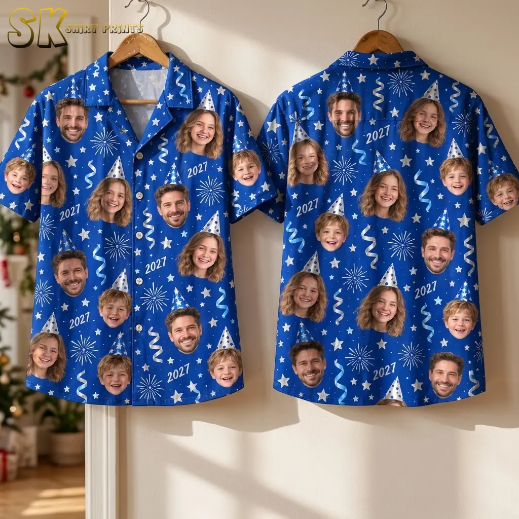 Two royal blue face-print shirts hang against a light wall, showing the front and back with stars, streamers, and 2027 text.