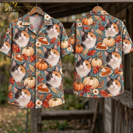 Front and back of a blue calico cat and pumpkin shirt hang from wooden hangers beneath a wooden beam in an outdoor setting.