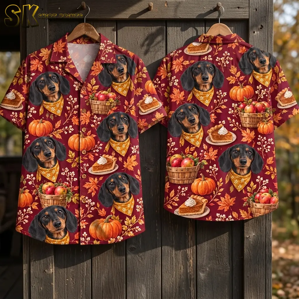 Front and back of maroon dachshund-print shirts hang on wooden hangers against a dark plank wall, displaying pumpkins, pie slices, and apple baskets.