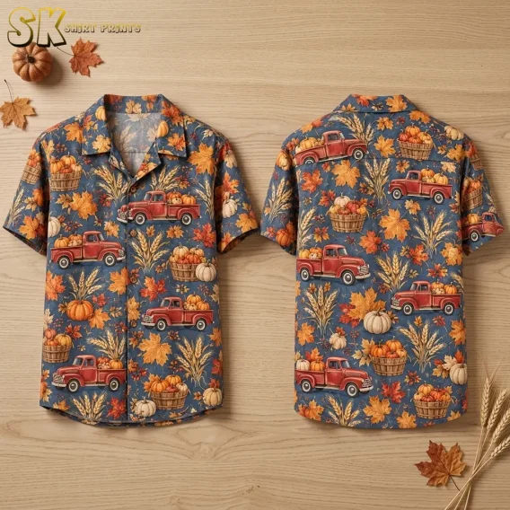 A blue-gray short-sleeve shirt lies front and back side by side on wood, showing red pumpkin trucks and autumn leaves.