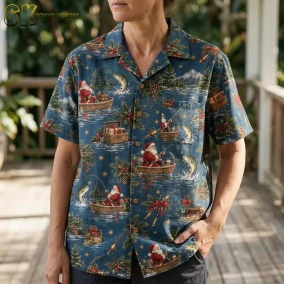 A woman wearing a hawaiian christmas shirt stands on a covered porch, and the close-up framing highlights the painterly Santa-fishing scenes, pine-branch clusters, and red berry details across the torso.