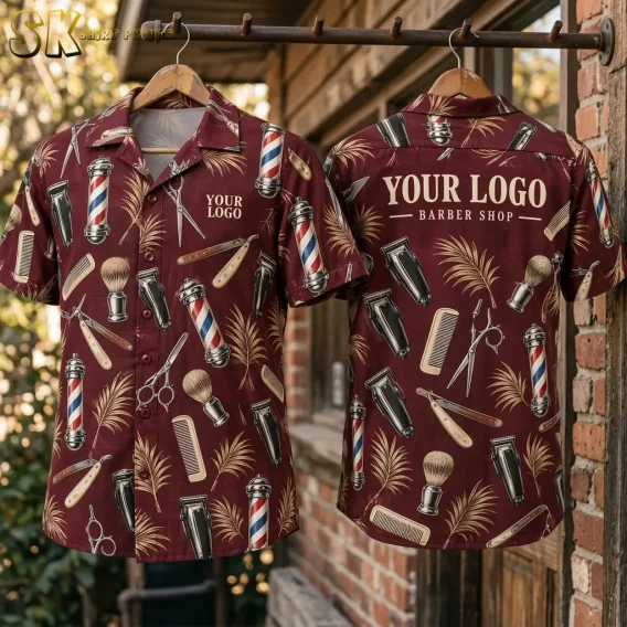 Two shirts hung side by side on a wooden rack against a brick wall show the front and back of the maroon hawaiian shirt logo design, with barber poles, combs, clippers, and the full back 'YOUR LOGO BARBER SHOP' text visible.
