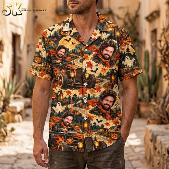 A man wearing the beige short-sleeve Hawaiian shirt featuring a repeating hot rod and Halloween pattern with pumpkins, ghosts, and bats across the fabric.