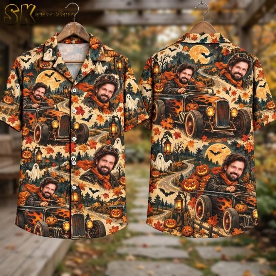 Flat lay of the shirt showing both the front and back panels side by side, with the full beige surface covered in repeating hot rod cars, pumpkins, floating ghosts, bats, lanterns, and autumn leaves in orange, black, and brown tones.