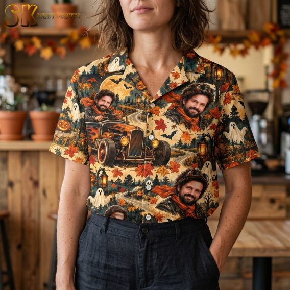 A close-up view of the shirt's fabric on a female model, showing the detailed painted-style artwork of the bearded man in goggles driving the flame-decorated vintage car, with bats and jack-o'-lanterns visible in the surrounding pattern.
