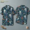 Front and back hanger view of a short-sleeve button-up shirt with a dark teal base, featuring large translucent jellyfish, fish skeletons, orange octopus tentacles, and crescent moons in an all-over watercolor-style pattern.