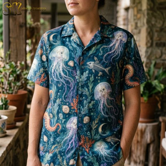 Close-up view of a woman wearing the shirt, showing the painterly detail of the translucent jellyfish, beige fish skeletons, and orange octopus tentacles against the dark teal fabric.