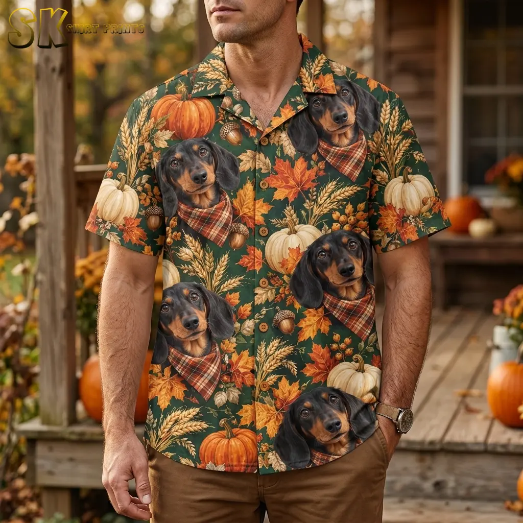 A man wears a green dachshund and pumpkin shirt with brown pants on a porch decorated with pumpkins.