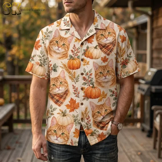 A man on a wooden deck wears a cream Thanksgiving Hawaiian shirt with large orange cat faces and pumpkins.