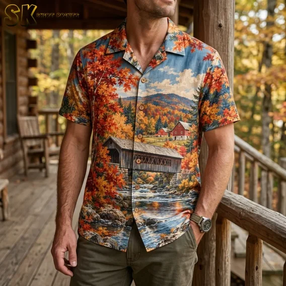 A man stands on a wooden porch wearing a short-sleeve button-up shirt with a covered bridge and autumn countryside print.