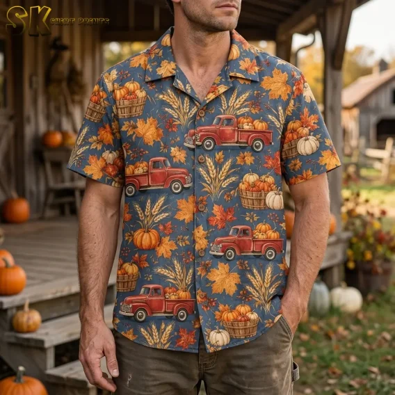 A man wears a Thanksgiving Hawaiian shirt with red pumpkin trucks on a wooden porch surrounded by pumpkins.