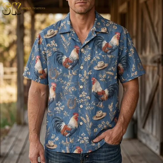 A man wears a blue short-sleeve rooster shirt with jeans on a wooden porch, resting one hand in his pocket.