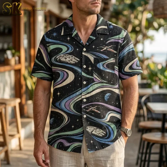 A man wears a black Star Wars Hawaiian shirt with spacecraft and colorful swirls, paired with light-colored shorts on a patio.