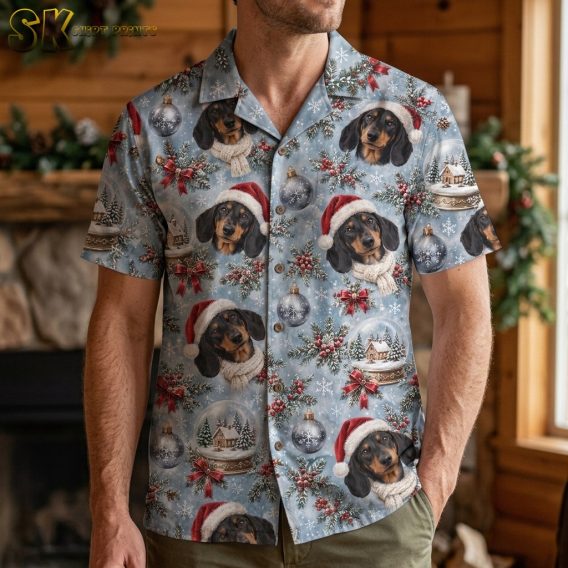 A man wearing a hawaiian shirt with a christmas santa claus dachshund print stands in a wood-paneled room decorated with garland, showing how the pattern sits across the chest and shoulders.