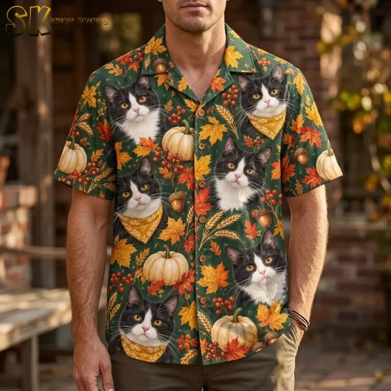 A man wears a dark green Thanksgiving Hawaiian shirt with large tuxedo cat faces and pumpkins, paired with brown pants.