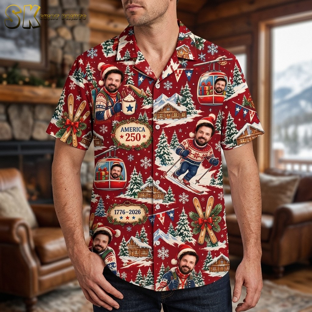 A man wearing the red all-over-print shirt stands in front of a cozy log-cabin interior, with the America 250 emblem and a large skiing figure visible across the chest.