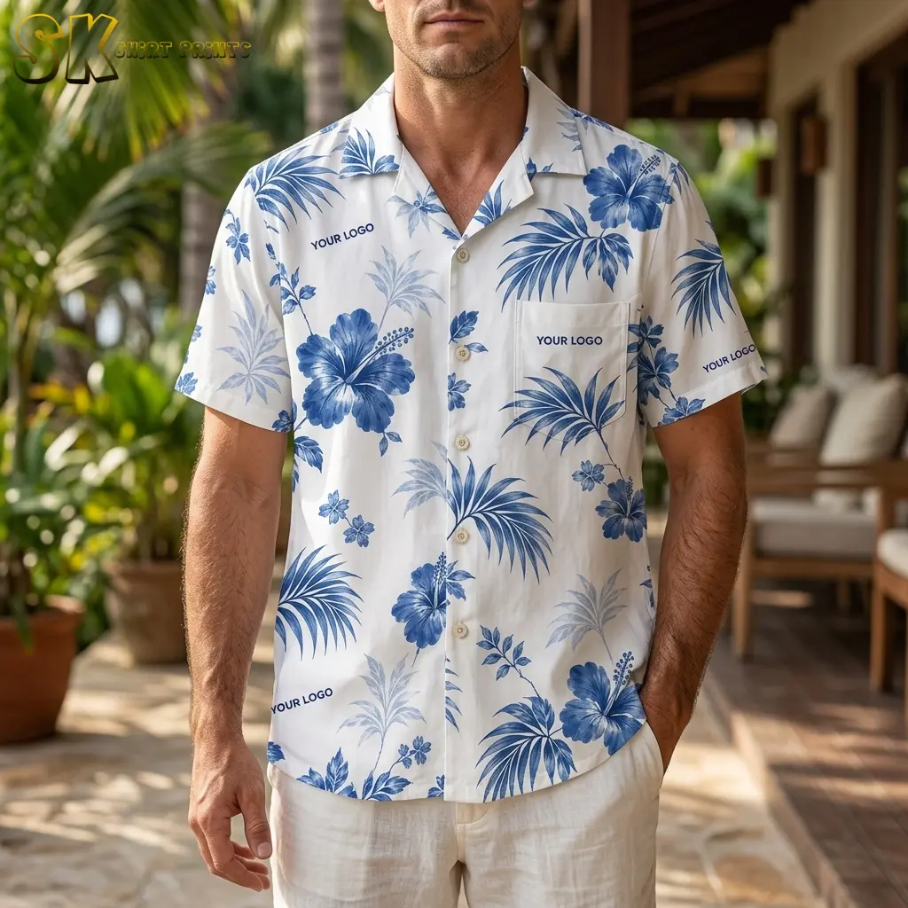 A man wearing a white custom Hawaiian shirt with your logo printed in several spots stands on an outdoor patio surrounded by tropical greenery, with bold blue hibiscus blooms visible across the chest and sleeves.