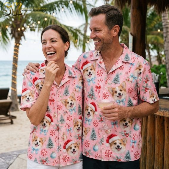 A laughing woman and a smiling man both wearing matching christmas hawaiian shirts stand together at an open-air beach bar with palm trees and string lights behind them.